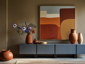 Living room interior featuring abstract artwork in terracotta, sand, and clay tones, ceramic vessels, low-profile cabinetry, and warm lighting expressing architectural calm and material-led design.