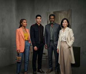 Four people standing together in a studio setting with a neutral background
