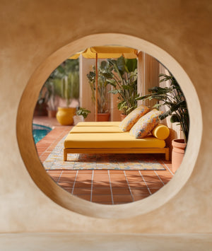 Yellow outdoor lounge chair with patterned cushions in a sunlit patio setting.