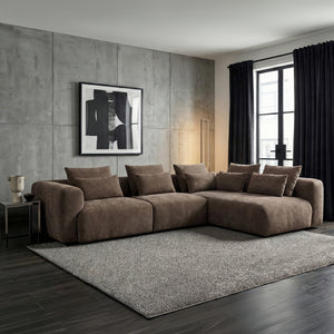 Brown sectional sofa in a modern living room with abstract art and large windows.