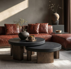 Modern living room with brown leather sofa, wooden coffee table, and decorative items.